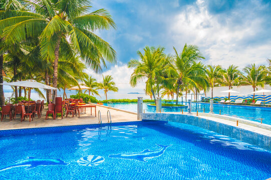pool on the beach by sea in a luxury resort for summer holidays. A pool on the ocean coast with palm trees in tropics in Asia.