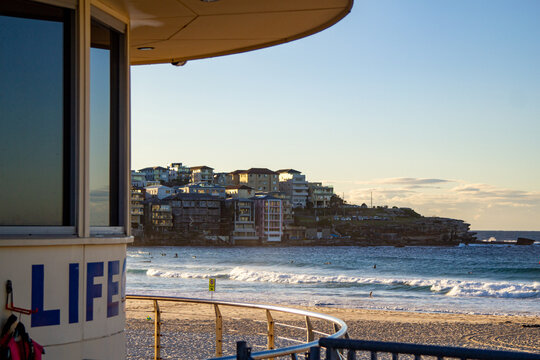 Lifeguard tower overlooking swimmers, breaking ocean waves, sandy beach and coastal apartments
