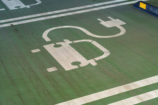 View of an electric vehicle charging symbol painted on a green parking space in Birmingham, England, United Kingdom.