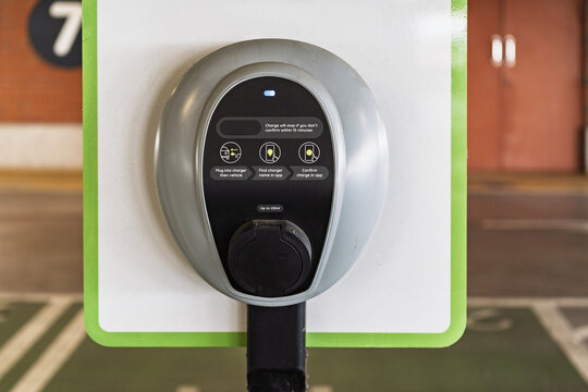 View of an electric vehicle charging station with clear instructional icons and a digital interface mounted on a wall in a parking garage in Birmingham, England, United Kingdom.
