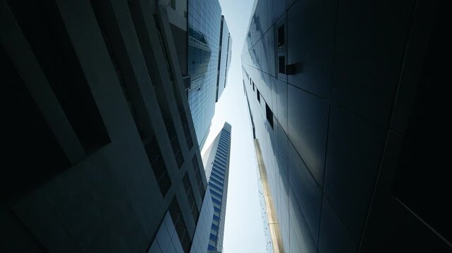 Dynamic upward perspective of modern glass office skyscrapers reflecting daylight.