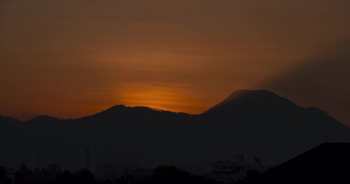 Timelapse of the sun rising behind the mountain silhouette