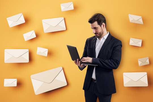 Businessman Using Laptop Surrounded by Floating Email Envelopes for Digital Communication, Online Business, and Marketing Concept on Orange Background.