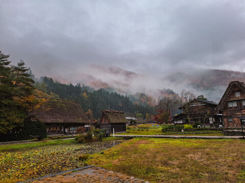 View of the traditional gassho-zukuri farmhouses with thatched roofs nestled in the misty mountains of Shirakawa-go during autumn in Shirakawa, Gifu, Japan.