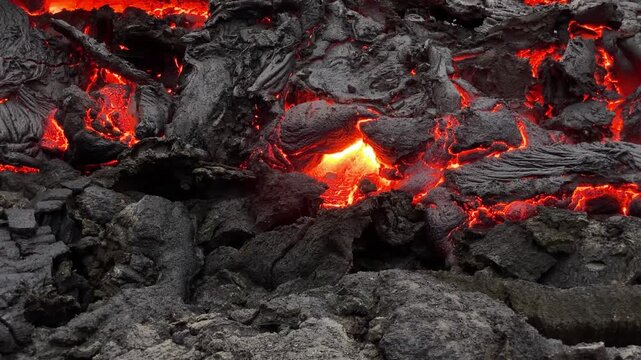 Nahaufnahme: Stein wird in gl&uuml;hend fl&uuml;ssige Lava des Fagradalsfjall Vulkans geworfen und versinkt