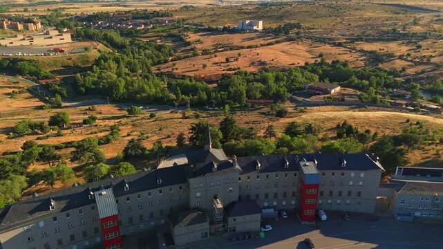 Apartment blocks near Avila, Spain, sit beside a tree lined valley bordered by dry fields and distant mountains.