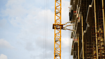 Tower crane beside a large high rise building under construction, representing urban development, engineering, infrastructure investment and modern real estate construction with generous copy space © belavinstock