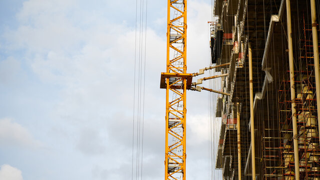 Tower crane beside a large high rise building under construction, representing urban development, engineering, infrastructure investment and modern real estate construction with generous copy space