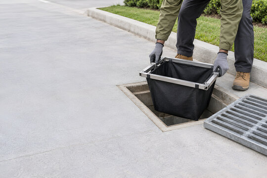 Stormwater Technician Installing a Geotextile Catch-Basin Filter Insert for Urban Runoff Pollution Prevention