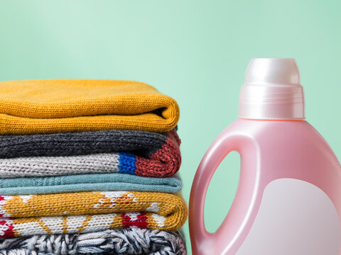 Stack of Folded Wool Sweaters with Laundry Detergent Bottle