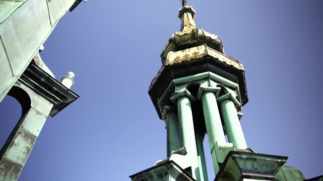 Close upward view of a decorative copper spire and weathered roof detail on a historic medieval tower
