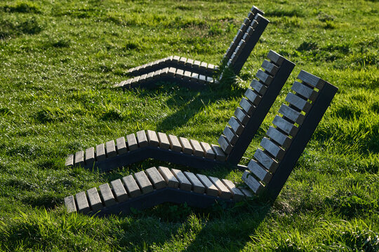 Wooden sun loungers on a green grass lawn in a public park in Gdansk, Poland