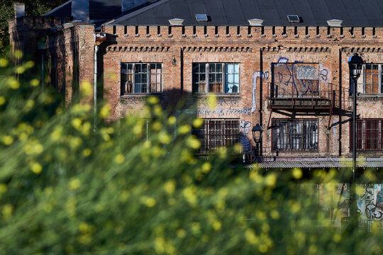 Brick facade of an old industrial building framed by green foliage in Gdansk, Poland