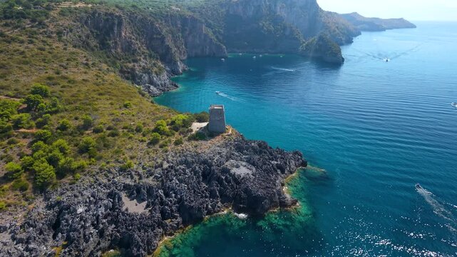 Marina di Camerota Cilento Italy 4K drone video. Torre del Zancale flyover over sea caves and Baia degli Infreschi cliffs with speed boats. Scenic travel b roll stock footage