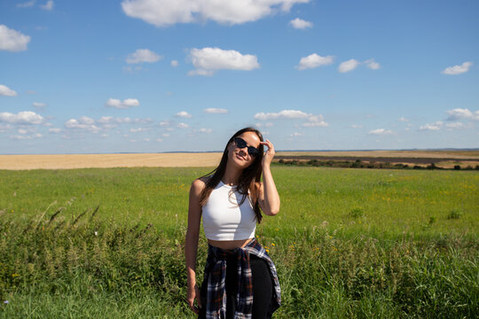 confident young woman adjusting her hair in a sunny field, combining casual fashion, natural beauty, self-acceptance and an authentic carefree lifestyle in the countryside