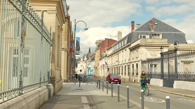 Cyclist riding along quiet street with historic buildings in Amiens France