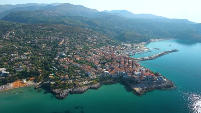 Marina di Camerota Cilento Italy drone left to right pan morning side light bay. Aerial overflight of peninsula town and beaches, turquoise sea reflection, Campania travel 4K video.