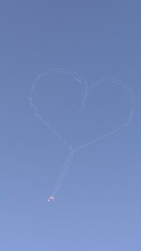 Heart Shaped Smoke Trail Drawn in Evening Sky by Stunt Planes with Flares, Aerobatic Airshow Display of Romantic Flying Symbols for Freedom Love and Aviation Event Background