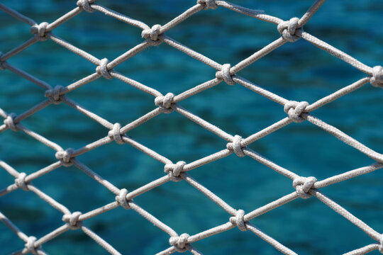 White rope safety net with knots over turquoise sea water