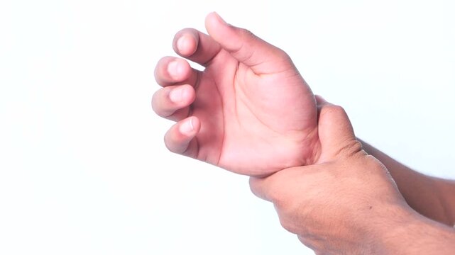 Close up video of young man suffering from wrist pain on white background in slow motion, hand massage for pain relief