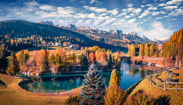 Sunny autumn view of Soraga lake. Beautiful morning cityscape of Soraga di Fassa village, Province of Trento, Italy, Europe. Spectacular outdoor scene of Dolomite Alps. Traveling concept background.