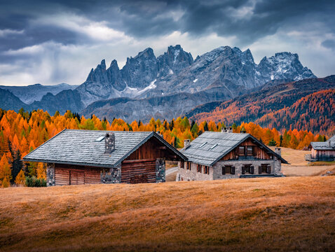 Breathtaking autumn view of wooden chalet on Fuchiade valley. Rainy morning scene of Dolomite Alps, Italy, Europe. Beauty of countryside concept background.