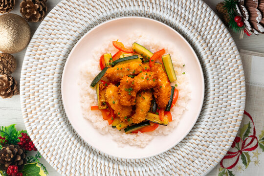 Battered chicken strips with vegetables and a white rice base. Overhead view of the table. Recipe for celebrating Christmas.