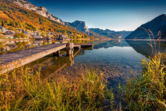 Empty wooden pier in a fishing village. Splendid morning scene of Grundlsee lake. Calm autumn view of Eastern Alps, Liezen District of Styria, Austria, Europe. Traveling concept background.