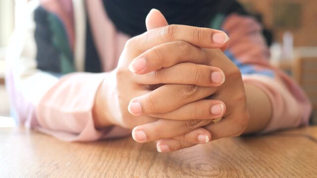 Close up shot of crossed hands on a wooden table, reflecting contemplation and thought