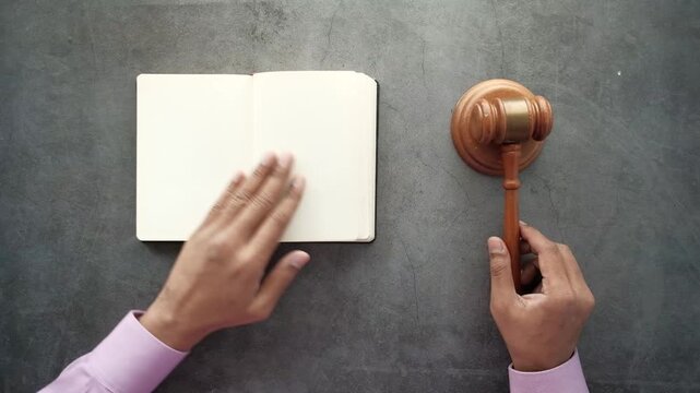 Lawyer hands turning pages in a notebook next to a wooden gavel on a desk