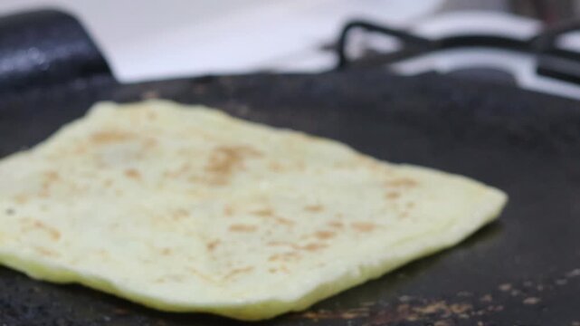 Moroccan msemen flatbread cooking and flipping on griddle