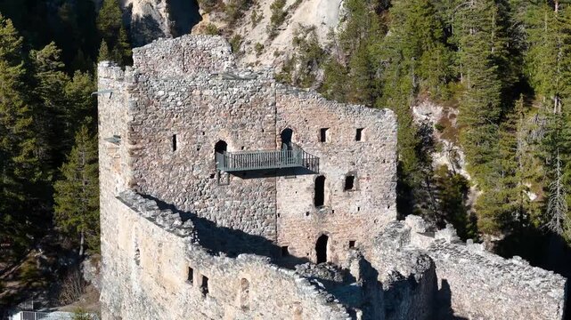 stone keep belfort castle ruins rocky bluff dense pine forest aerial drone pass arched window openings broken battlements viewing platform canopy graubunden switzerland surava albula valley
