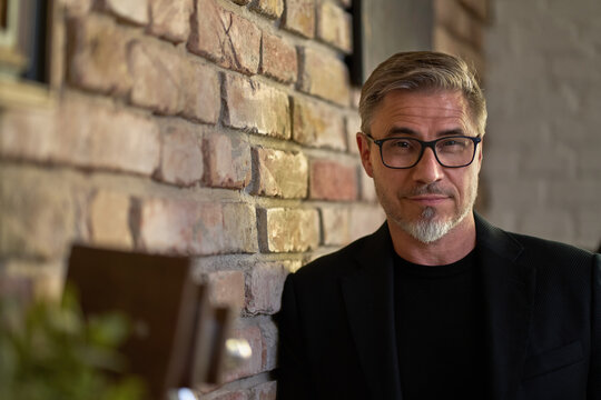 Business portrait - confident smiling businessman at loft office or home. Mature age, middle age, mid adult man in 50s, white caucasian,
