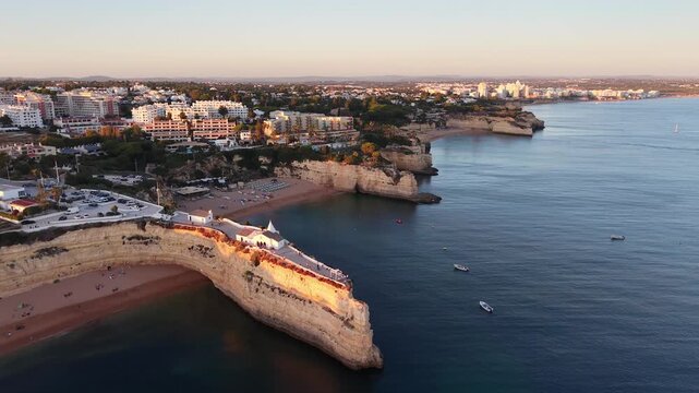 Aerial view of Nossa Senhora da Rocha chapel with coastline at sunset in Algarve Portugal