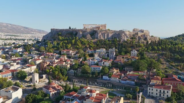 Stunning aerial footage revealing the ancient Acropolis with the Parthenon temple, majestically overlooking the historic Plaka district and the sprawling city of Athens under a clear sky