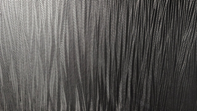 Abstract close-up of a dark textured surface with repeating chevron patterns, likely woven fabric or rubber.