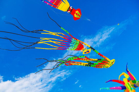 Flying colorful kites in the blue sky with clouds. Kite festival. The concept of freedom and summer relaxation