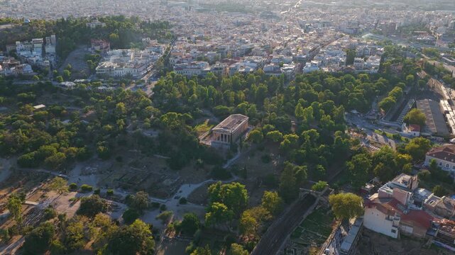 Stunning aerial footage showing the ancient Temple of Hephaestus within the historic Agora of Athens, beautifully contrasted against the sprawling urban landscape of the modern city at sunrise