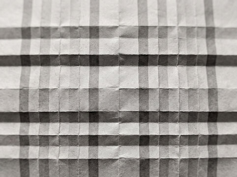Minimalist folded paper background featuring geometric plaid pattern in grey tones