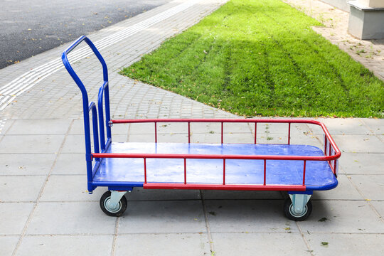 Large empty platform trolley for manual transportation of bulky cargo, industrial metal hand cart for heavy goods, warehouse equipment.