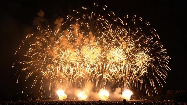 Spectacular golden fireworks display exploding over a large crowd during a night time celebration