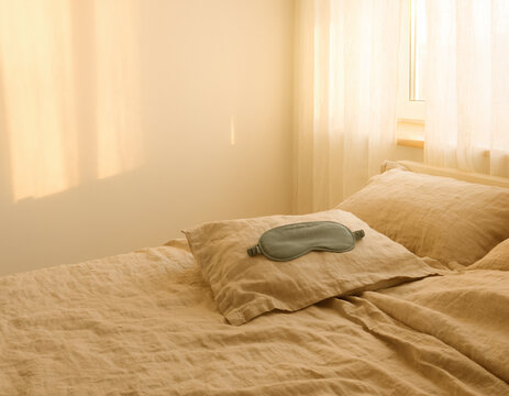 Sage sleep mask on linen bedding in warm morning light