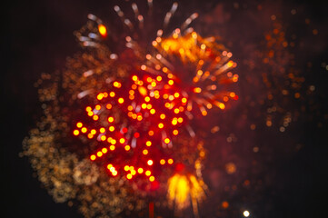 Red fireworks display captured out of focus against dark sky, creating soft glowing bursts and an abstract bokeh effect © alexkoral