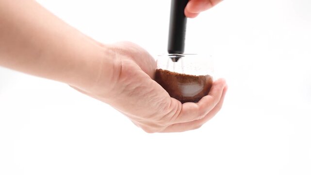 Morning Coffee Routine. close up of a man distributing ground coffee in a portafilter using distributor needle.