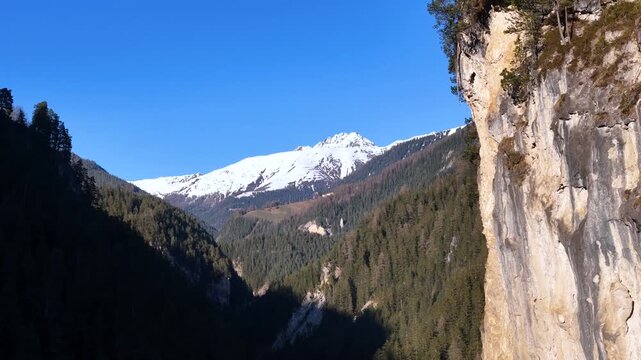 gorge cuts through forested alpine terrain near filisur switzerland limestone cliff rises snowcapped peak fills valley gap pine forest blankets aerial drone footage clear sky landscape graubunden