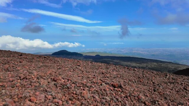 Aerial timelapse over red volcanic slope of Mount Etna overlooking Catania plain and sea in Sicily