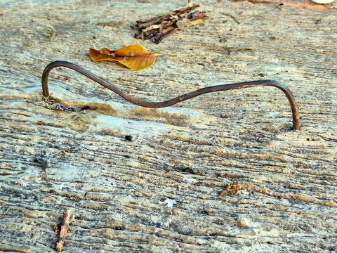Rusted metal wire embedded in a rough concrete and stone surface