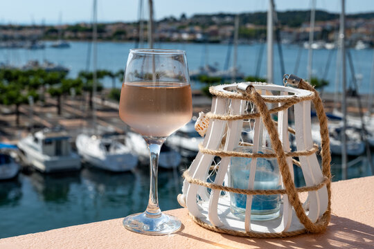 Glass of cold rose wine and view on Cap d'Agde marina with boats, Mediterranean Occitanie, Languedoc wine production, summer vacation destination and tasting of regional wines