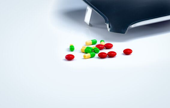 Red tablets and green-yellow capsules pills with drug tray on white table. Pharmaceutical industry. Vitamins and supplements. Pharmaceutics concept. Pharmacy products. Healthcare and medication.