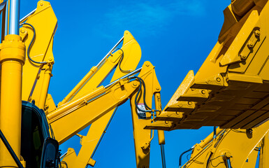 Yellow backhoe with hydraulic piston arm against clear blue sky. Heavy machine for excavation in construction site. Hydraulic machinery. Huge bulldozer. Heavy industry © Fahroni